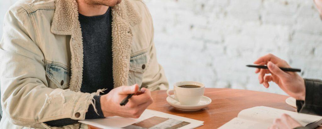 lender-borrower-discussing-over-coffee-seo A lender and borrower have a meeting in a coffee shop to discuss an SBA 7(a) loan.
