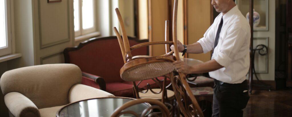 A restaurant owner puts up chairs on the tables in their restaurant.
