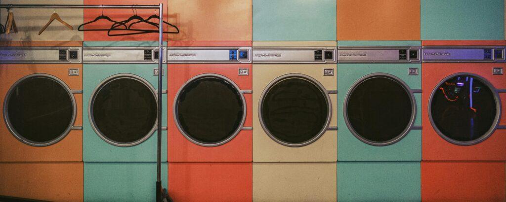 A line of colored washing machines at a laundromat.