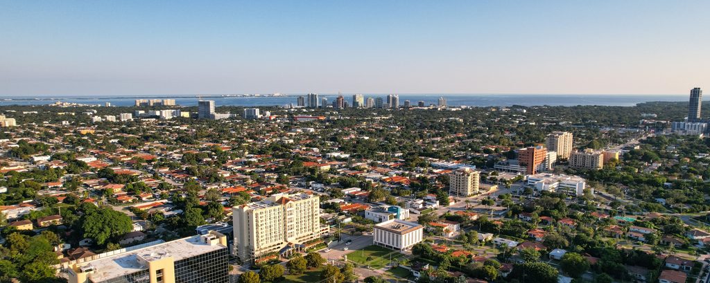 Miami-seo The city of Miami, with various neighborhoods in the foreground and tall buildings and the ocean in the distance.