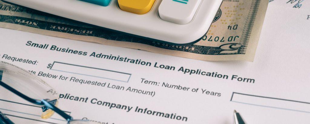 sba-loan-consultant-1-seo An SBA loan application form, with a calculator, glasses, and cash also visible.